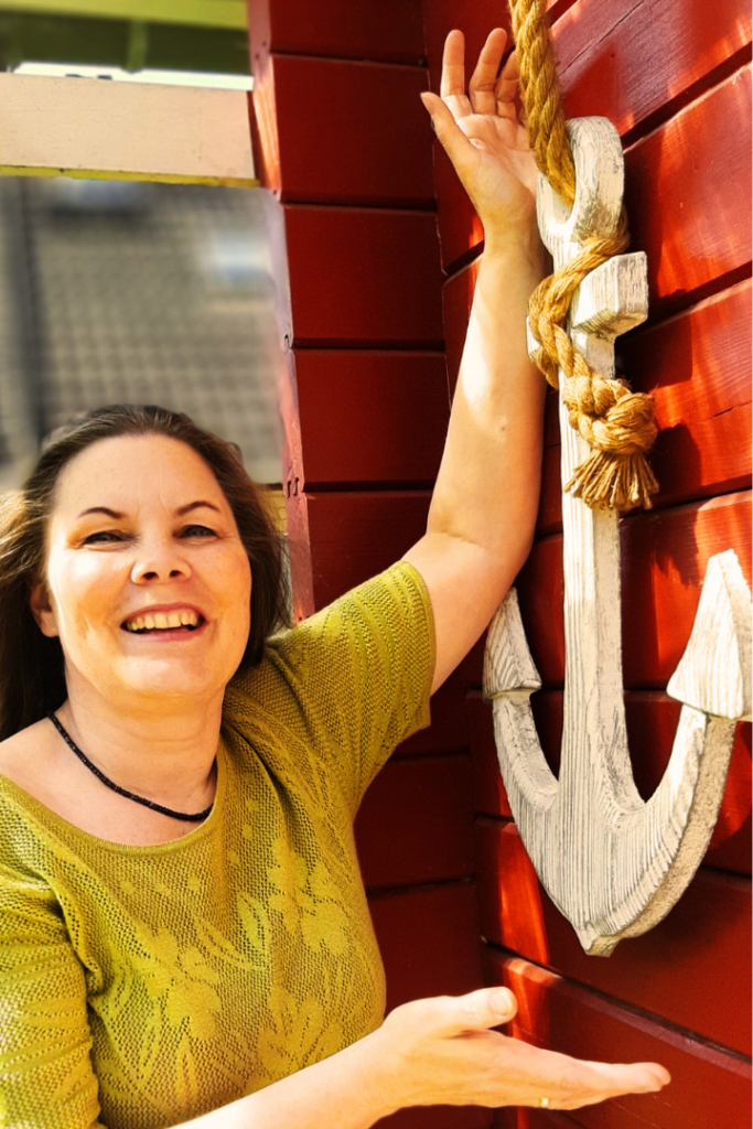 Viola Ehlers steht vor ihrer Praxis und hält einen Anker in den Händen. Sie bietet ihre Resilienztraining als Heilpraktiker für Psychotherapie Ahrensburg an.