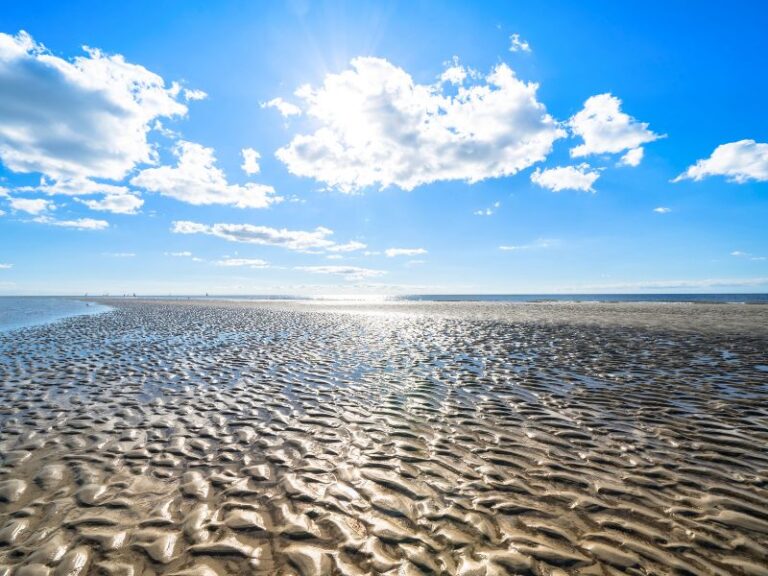 Ein weiter sonniger Sandstrand am Meer symbolisiert die gewonnene innere Klarheit durch eine fundierte psychologische Beratung.